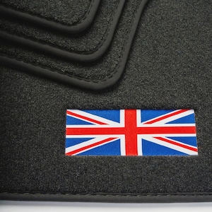 Pode incluir: Tapetes de carro cinza escuro com acabamento preto. Os tapetes apresentam um patch costurado da bandeira Union Jack em vermelho, branco e azul.