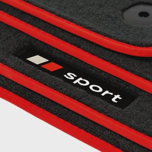 Könnte beinhalten: Nahaufnahme einer dunkelgrauen Auto-Fußmatte mit roter Umrandung. Die Matte hat ein schwarzes rechteckiges Etikett mit dem Wort "Sport" in Weiß und ein rot-weißes Logo.