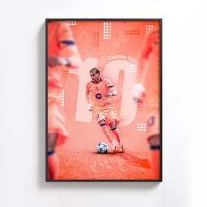 May include: Framed poster featuring a soccer player in an orange uniform with the number 10. The player is dribbling a soccer ball on a reddish-orange background. The name "Lamine Yamal" is visible. The poster has a black frame.