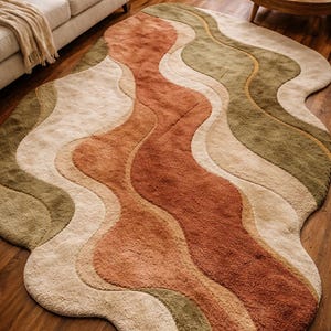 Könnte beinhalten: Ein wellenförmiger, abstrakter Teppich in Rost-, Beige- und Olivgrüntönen. Der Teppich hat eine weiche, plüschige Textur und eine organische Form, die der Raumdekoration eine moderne Note verleiht.