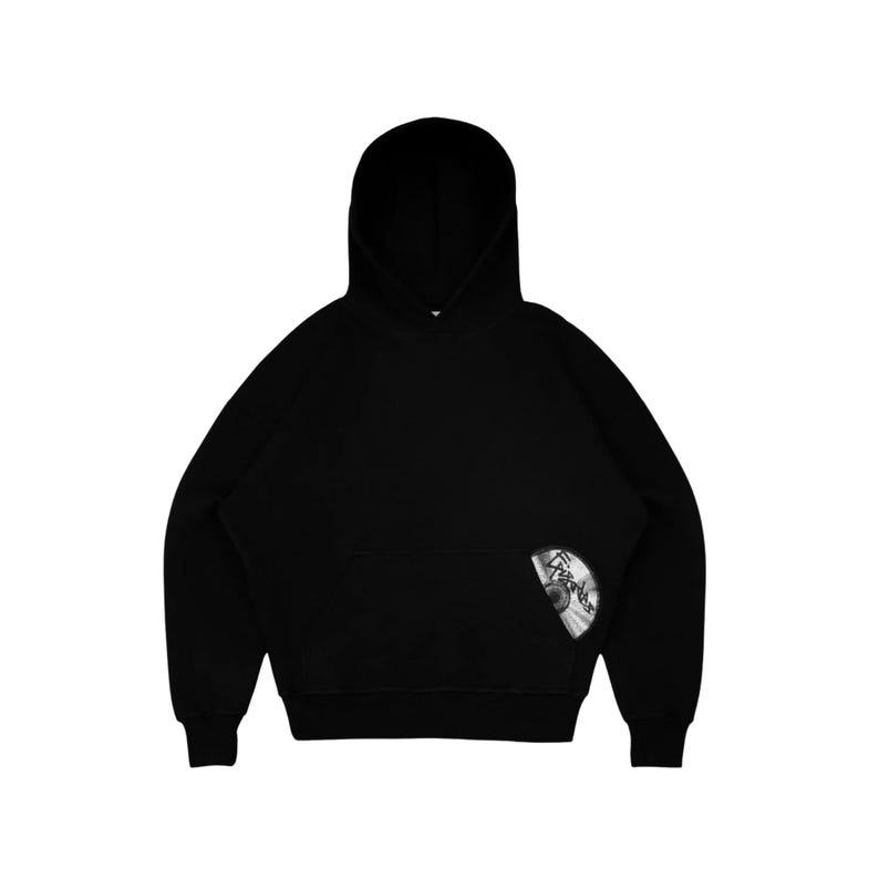 Puede incluir: Sudadera con capucha negra con bolsillo delantero y capucha. Un peque&ntilde;o gr&aacute;fico circular est&aacute; en el lado inferior derecho de la sudadera con capucha. El gr&aacute;fico parece ser una imagen en blanco y negro de un CD.