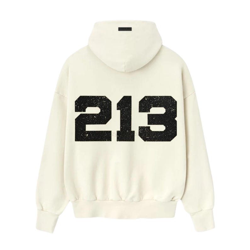 May include: Cream-colored hoodie with the number "213" printed in distressed black on the back. The hoodie features a hood and long sleeves. A small black rectangular detail is on the hood.