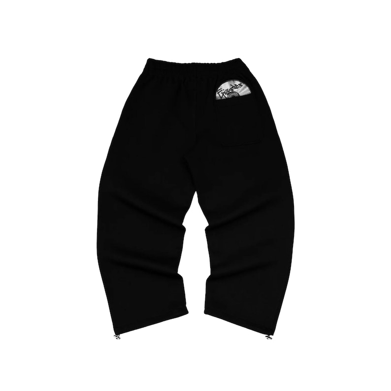Puede incluir: Pantalones deportivos negros con cintura el&aacute;stica y corte holgado. Los pantalones tienen un peque&ntilde;o bolsillo en la parte trasera con un dise&ntilde;o gr&aacute;fico. La parte inferior de los pantalones tiene un detalle de cremallera. Ropa casual.