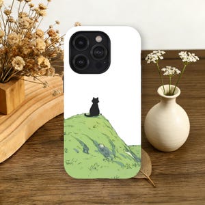 Könnte beinhalten: Weißes Handycase mit einer schwarzen Katzen-Silhouette auf einem grünen Hügel. Das Design ist eine minimalistische Illustration im Cartoon-Stil. Das Handycase hat eine glänzende Oberfläche und einen Kameraausschnitt.