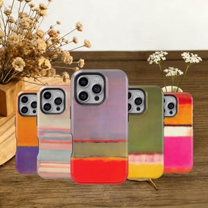 May include: Five mobile phone cases with abstract art designs. The cases feature a variety of colours, including orange, purple, pink, green, and yellow. The cases are arranged on a wooden surface.