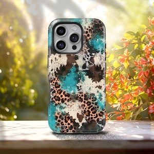Könnte beinhalten: Eine Schutzhülle für ein Telefon mit einem farbenfrohen Design. Die Hülle zeigt eine Mischung aus Türkis, Braun und Creme mit einem Leopardenmuster. Sie hat einen schwarzen Rand und einen Kameraausschnitt.