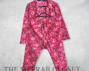 Peut inclure: Ensemble de pyjama floral rouge, composé d'un haut boutonné et d'un pantalon assorti. L'ensemble présente un motif floral vibrant dans les tons de rose et de vert. Le texte "THE MERAB CLOSET Curated Elegance" est visible en bas.