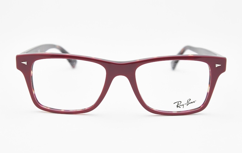 May include: Burgundy-colored eyeglasses with a rectangular frame. The glasses have a tortoiseshell pattern on the inner frame and temples. The Ray-Ban logo is visible on the right lens.