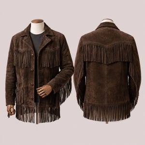 Puede incluir: Una chaqueta de ante marrón oscuro con largos flecos en el pecho, la espalda y el dobladillo. La chaqueta incluye un cuello, cierre frontal de botones y mangas largas con detalles de flecos, exhibida sobre un maniquí.