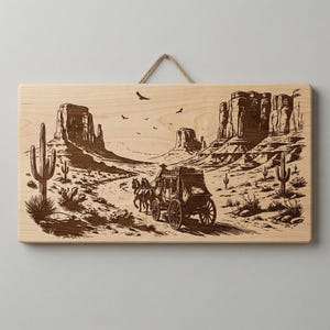 May include: Wooden wall art featuring a detailed engraving of a stagecoach traveling through a desert landscape. The artwork depicts cacti, rock formations, and birds in flight, all rendered in shades of brown. A rope is attached for hanging.