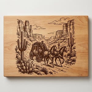 May include: A wooden cutting board with a detailed engraving of a stagecoach pulled by two horses through a desert landscape. The design features cacti, rock formations, and a driver. The board has a light wood grain.