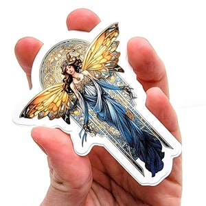 May include: A sticker featuring a colorful illustration of a fairy with large wings, wearing a blue dress and a crown. The fairy is surrounded by a decorative, stained glass-like frame.