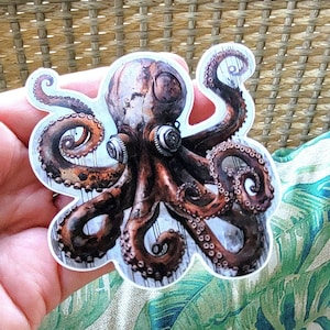 May include: A rusty brown octopus sticker with steampunk-inspired details, including gears and pipes. The octopus has eight tentacles and two large, round eyes.