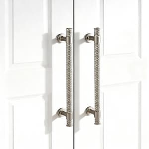 May include: Two brushed nickel cabinet door handles. Each handle has a long, textured grip with a cylindrical design. The handles are mounted on a white cabinet door. The handles are approximately 12 inches long.