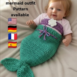 以下が含まれることがあります： 手作りのかぎ針編みの人魚の衣装を着た新生児。衣装は、紫色のトップスと白い花のアクセントが付いた、ティールグリーンです。画像には「Newborn mermaid outfit Pattern available」というテキストが含まれています。