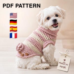May include: A white dog wearing a pink and cream striped crochet sweater with a turtleneck, a small decorative flower on the back, and two brown buttons. The image includes the text PDF PATTERN, four national flags, and a tag reading mallow mesh.