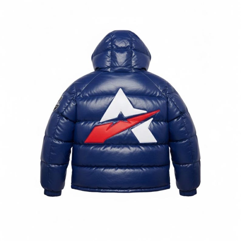 K&ouml;nnte beinhalten: Marineblaue Steppjacke mit Kapuze. Auf der R&uuml;ckseite der Jacke befindet sich ein wei&szlig;es und rotes Logo. Die Jacke hat ein gl&auml;nzendes, gestepptes Aussehen. Die Jacke ist f&uuml;r kaltes Wetter konzipiert.
