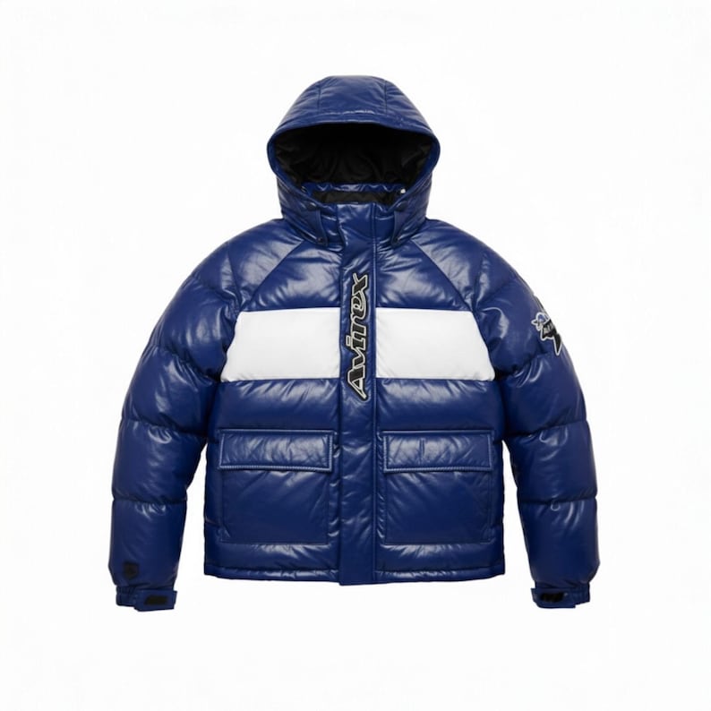 K&ouml;nnte beinhalten: Gl&auml;nzende, blaue Pufferjacke mit Kapuze und zwei Vordertaschen. Die Jacke hat einen wei&szlig;en Streifen &uuml;ber der Brust und das Wort "Avirex" in wei&szlig;en Buchstaben. Auf dem rechten &Auml;rmel befindet sich ein kleines Emblem.