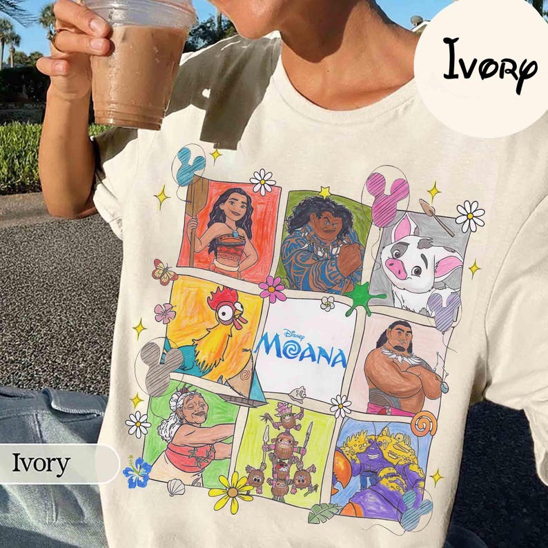 K&ouml;nnte beinhalten: Elfenbeinfarbenes T-Shirt mit einem farbenfrohen Grafikdesign von Charakteren aus dem Disney-Film Moana. Das Design zeigt Illustrationen von Moana, Maui, Pua, Hei Hei und anderen, mit dem Logo des Films in der Mitte.