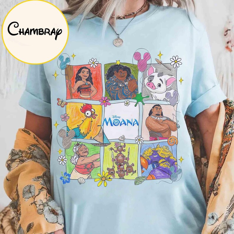 K&ouml;nnte beinhalten: Hellblaues T-Shirt mit einem farbenfrohen Grafikdesign von Charakteren aus dem Disney-Film Moana. Das Design zeigt Moana, Maui, Pua, Hei Hei und andere, mit dem Filmtitel in der Mitte. Das T-Shirt hat kurze &Auml;rmel.