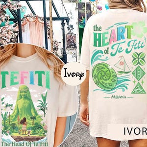 May include: Ivory-colored t-shirt featuring the text "TEFITI" in green and pink letters. The front graphic depicts a green figure and the text "The Head Of Te Fiti". The back of the shirt displays "the HEART of Te Fiti" and "MOANA".