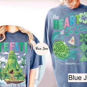 May include: Blue denim-colored t-shirts with graphics from the animated film Moana. The front features the word "TEFITI" in green, pink, and blue, with a green character and the text "The Head Of Te Fiti". The back displays "the HEART of Te Fiti" and other graphics.
