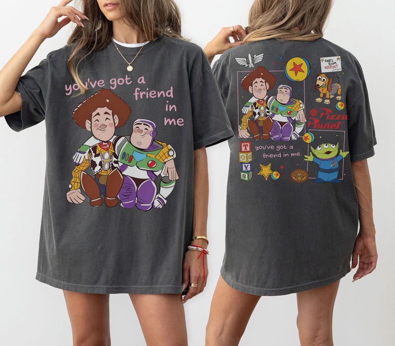 Op de afbeelding: Donkergrijs T-shirt met een afbeelding van Woody en Buzz Lightyear en de tekst "you've got a friend in me." De achterkant van het shirt heeft extra Toy Story graphics. Het T-shirt heeft een relaxte pasvorm.