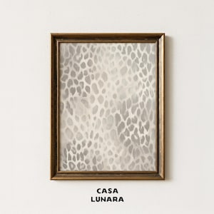 May include: A rectangular wall art piece in a dark brown wooden frame featuring a vertical abstract print with a grey and white leopard spot pattern. The text CASA LUNARA is printed in black capital letters centered below the framed artwork.