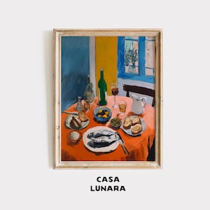 Puede incluir: Una lámina enmarcada titulada CASA LUNARA que representa un bodegón vibrante sobre un mantel naranja. La escena muestra dos pescados enteros en un plato blanco, cuencos con aceitunas, pan en rodajas, una botella de vino verde y una jarra blanca.