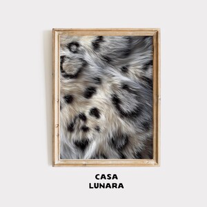 May include: A rectangular wall art print in a light-toned wooden frame featuring a high-resolution close-up of snow leopard fur with a pattern of black spots on a cream and grey background. The text CASA LUNARA is printed below the frame.