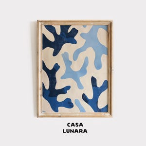 May include: Abstract art print featuring organic shapes in shades of blue against a cream background. The artwork is framed in a light-colored wooden frame. The text "CASA LUNARA" is printed at the bottom of the image.