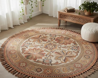 May include: A round area rug with a floral design in shades of beige, orange, and brown. The rug has a fringed edge and a detailed pattern of flowers and geometric shapes. The rug is a decorative home accent.