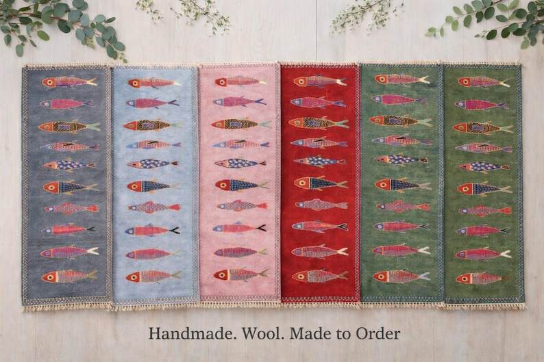 May include: Six rectangular wool runners arranged side-by-side, each featuring a repeating pattern of small fish in various colors. The runners are colored dark gray, light blue, pink, red, green, and dark green. Text reads: Handmade. Wool. Made to Order.