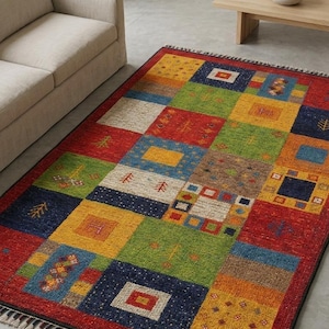 May include: A rectangular area rug with a patchwork design. The rug features squares in red, blue, green, yellow, and brown. Some squares have geometric patterns and tree-like designs. The rug has a fringe border.