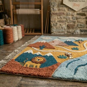 May include: A rectangular tufted rug featuring a landscape design with a lion, mountains, a winding blue river, and small houses. The rug has a textured surface with a color palette of mustard yellow, blue, brown, and cream, finished with fringe.