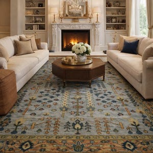 May include: A living room with a light blue patterned rug, two cream-colored sofas, and a fireplace. The rug features a detailed design with orange, blue, and yellow accents. A chandelier hangs above a wooden coffee table.