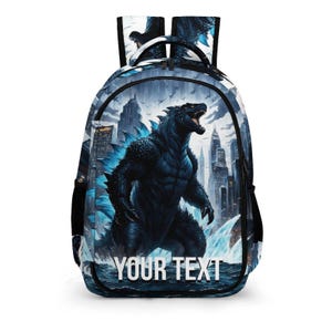 May include: A backpack featuring a graphic print of a large, dark, scaled creature with blue glowing dorsal fins standing in a city landscape with water in the foreground. The words YOUR TEXT are printed in white capital letters at the bottom.