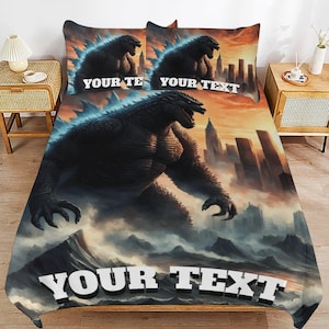 May include: A bedding set featuring a large, dark, muscular monster standing in a city landscape with a sunset sky. The design includes the text YOUR TEXT on the two pillowcases and the bottom of the comforter in bold, white, block lettering.