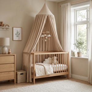 May include: A light wood crib with a canopy, a mobile, and a neutral-toned quilt. The nursery also features a dresser, a shelf with a rainbow, and a framed botanical print. A plush cloud and a stuffed animal are in the crib.