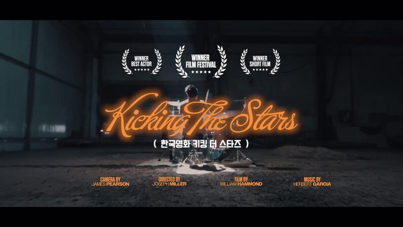 May include: A movie poster for "Kicking The Stars" featuring a drummer playing a drum set. The title is in orange neon script. The poster includes the text "Winner Best Actor", "Winner Film Festival", and "Winner Short Film".
