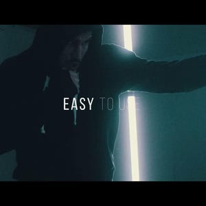 May include: A person in a dark hoodie is shown in a dimly lit room, punching a heavy bag. The text "EASY TO USE" is displayed in white. The scene is illuminated by a vertical neon light.