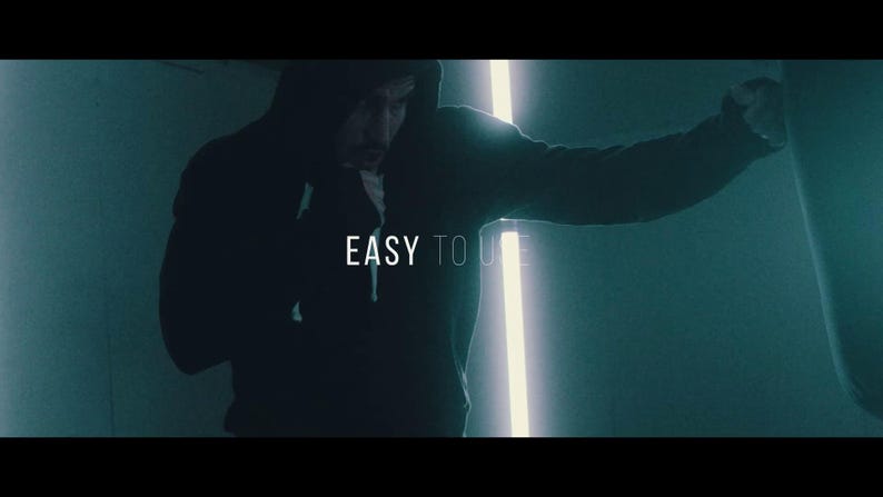 May include: A person in a dark hoodie is shown in a dimly lit room, punching a heavy bag. The text "EASY TO USE" is displayed in white. The scene is illuminated by a vertical neon light.