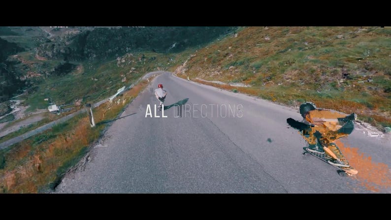 May include: A scenic shot of a winding mountain road with two skateboarders. One is riding down the road, and the other is performing a trick. The text "ALL DIRECTIONS" is overlaid on the road.