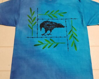 New design with a raven, yellow green leafy fronds and barb wire printed on a man's large t-shirt, dyed with brilliant blues, robin egg blue