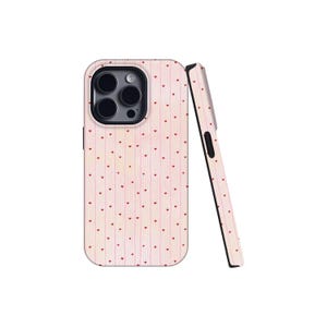 May include: A smartphone case featuring a light pink background with thin vertical white stripes and a repeating pattern of tiny red hearts. The case includes a cutout for a triple-lens camera system and shows a side profile view of the edge.