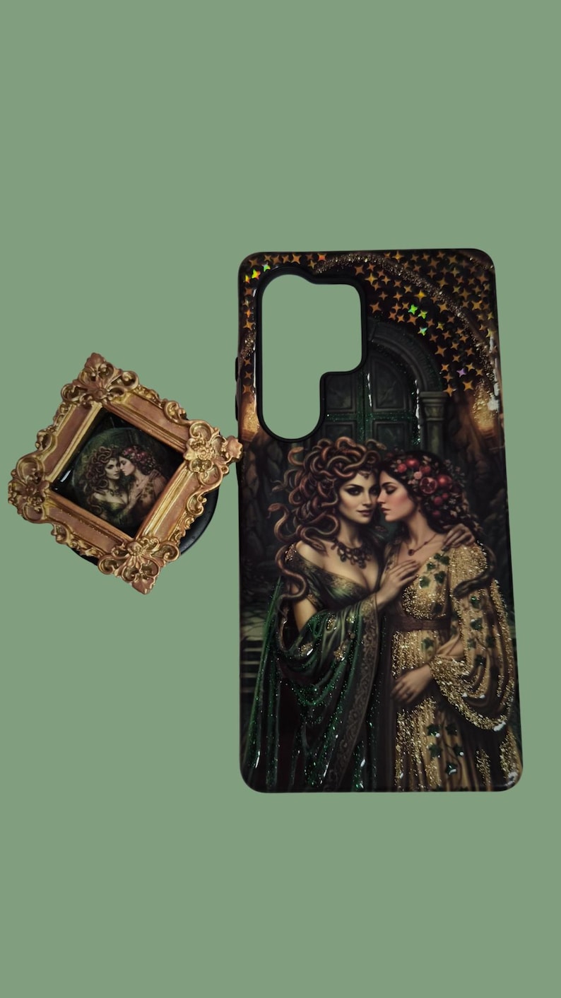 Pu&ograve; includere: Una cover rettangolare per telefono e un supporto quadrato con un'illustrazione scura e ornata di due figure con lunghi capelli fluenti in abiti verdi e dorati. La cover presenta un ritaglio per l'obiettivo della fotocamera.