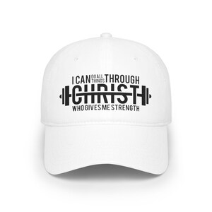 Könnte beinhalten: Eine weiße Baseballkappe mit gebogenem Schirm. Auf der Kappe steht in schwarzer Schrift "I CAN DO ALL THINGS THROUGH CHRIST WHO GIVES ME STRENGTH", wobei "CHRIST" als Hantel gestaltet ist.