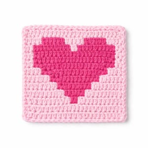 May include: A square, crocheted coaster featuring a pixelated heart design. The heart is a vibrant shade of pink, set against a lighter pink background. The coaster is handmade, showcasing a textured, handcrafted appearance.