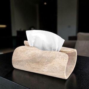Peut inclure: Un porte-boîte à mouchoirs rectangulaire fabriqué en pierre de travertin beige avec une texture naturelle poreuse. Le support présente un design incurvé à extrémités ouvertes permettant de tirer un mouchoir blanc par l'ouverture centrale.
