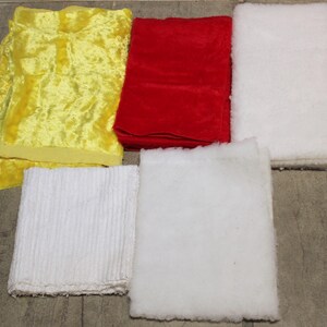 May include: An overhead shot displays five fabric swatches. A folded yellow velvet piece is on the left. A folded red velvet piece is in the center. Two white, fluffy pieces are on the right. A white, ribbed piece is at the bottom.